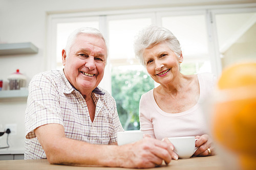 Portrait of senior couple smiling while having coffee in kitchen
