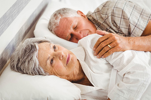 Senior man sleeping while woman still awake on bed in bed room