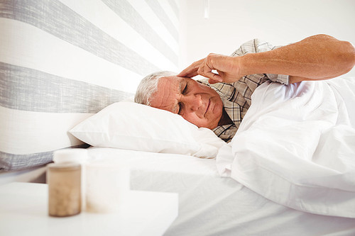 Frustrated senior man lying on bed in bedroom