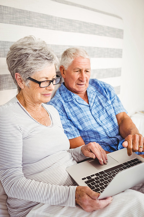 Senior couple using laptop in bedroom