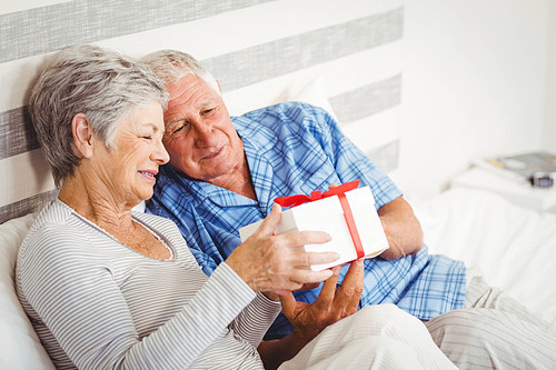 Senior couple looking at gift box in bedroom