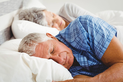 Senior couple sleeping on bed in bedroom