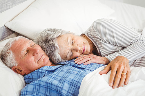 Senior couple sleeping on bed in bedroom