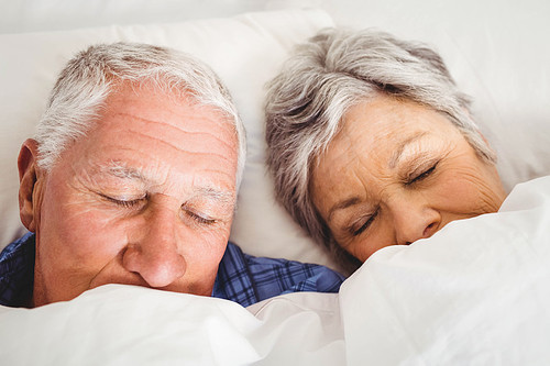 Senior couple sleeping on bed in bedroom