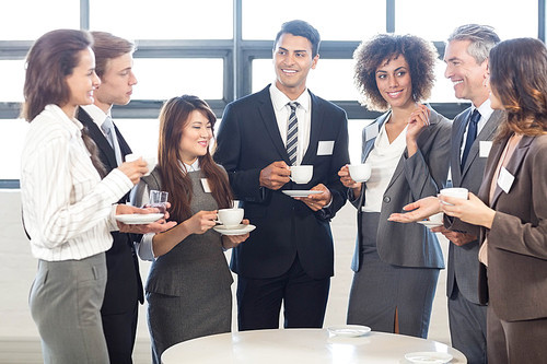 Businesspeople having tea and interacting during breaktime in office