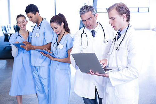 Medical team discussing and using laptop and digital tablet in hospital