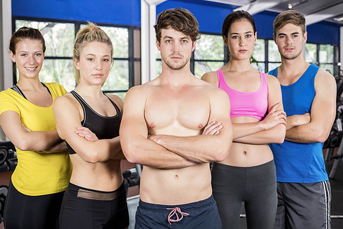Athletic men and women posing with arms crossed at crossfit gym