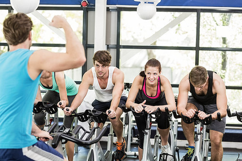 Fit group of people using exercise bike together in crossfit