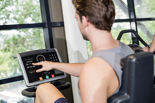 Fit man doing exercise bike at gym