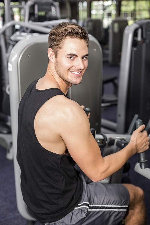 Fit man using weight machine at gym