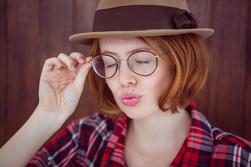 hipster woman osing with her eyes closed against a wooden background