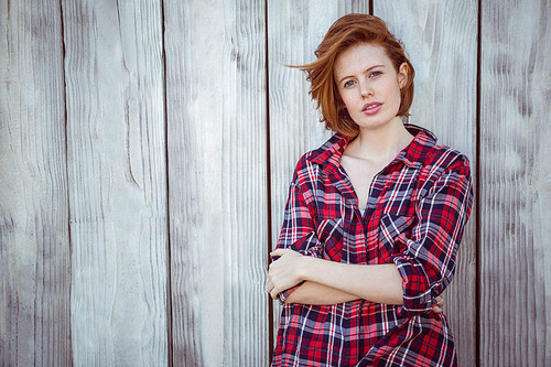 beautiful hipster woman with her arms crossed, against a wooden background