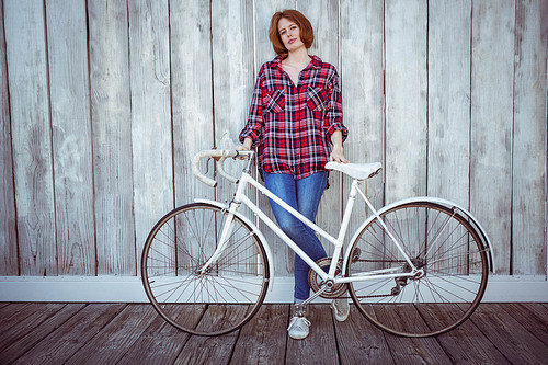 beautiful hipster woman with a bicycle, standing against a wooden background