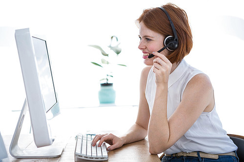 smiling hipster business woman wearing a headset and typing