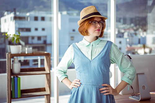 Pretty hipster wearing nerd glasses and hat in front of window