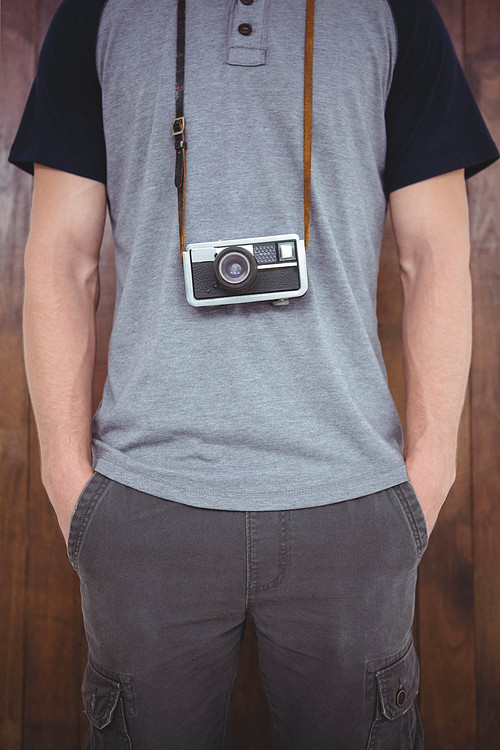 Handsome hipster holding retro camera around hipster neck