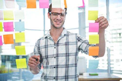 Hipster man looking at post-it in office
