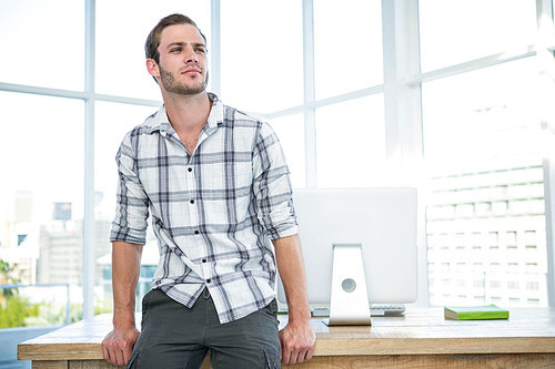 Hipster man sitting on desk in office