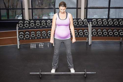Determined woman lifting barbell at the gym