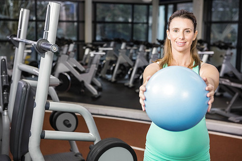Smiling blonde holding medicine ball at the gym