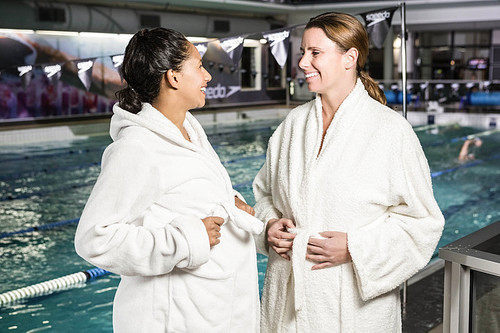 Pregnant women with bathrobe talking at the swimming pool