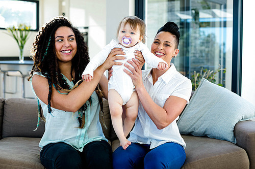 Lesbian couple playing with their baby in living room