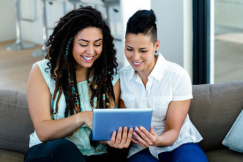 Lesbian couple using digital tablet in living room