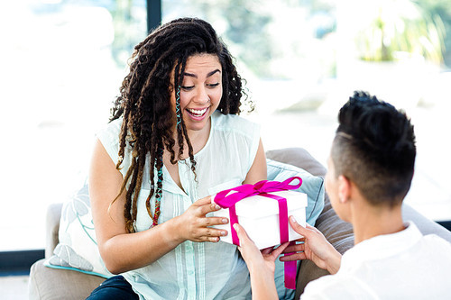 Woman receiving a gift from her partner in living room