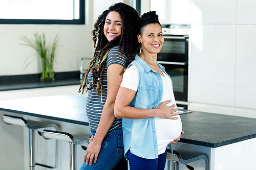 유토이미지 | Pregnant Lesbian Couple Standing Back To Back And Smiling In ...