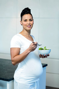 Portrait of pregnant woman holding a bowl of salad and smiling