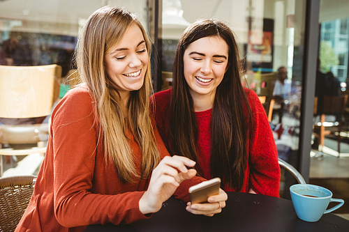 Friends looking at smartphone in cafe