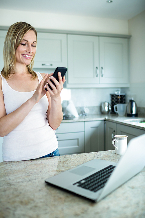 Pretty blonde woman looking at smartphone at home