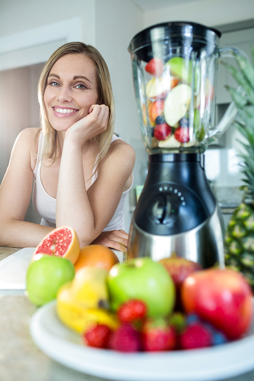 Pretty blonde woman happy to prepare a smoothie in the kitchen