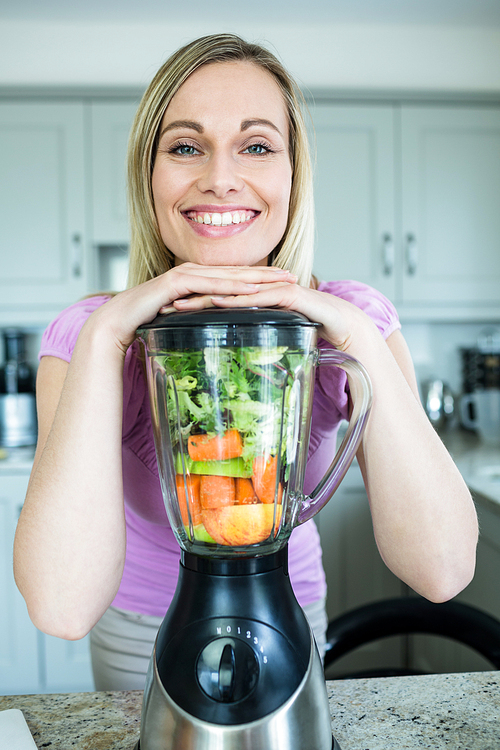 Pretty blonde woman preparing a smoothie in the kitchen