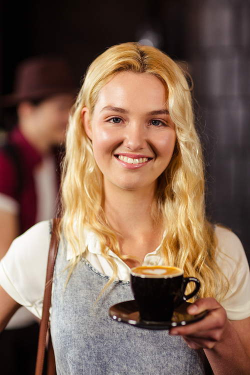 Portrait of smiling pretty customer holding cup of coffee at coffee shop