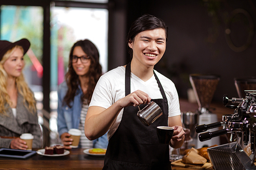Smiling waiter making cup of coffee at the coffee shop