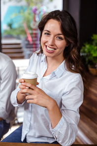 Smiling woman holding a cup of coffee in a cafe