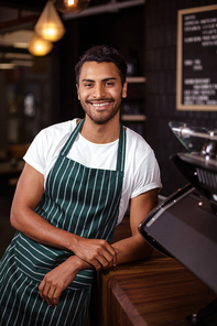 Smiling barista leaning against counter in a cafe