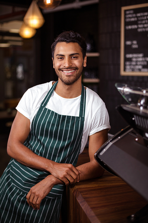Smiling barista leaning against counter in a cafe