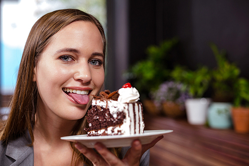 Sweet tooth woman holding piece of cake in the bar