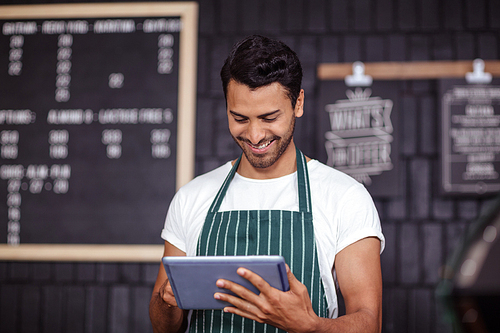 Smiling barista using tablet in the bar