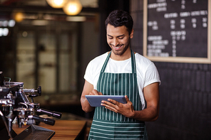 Smiling barista using tablet in the bar