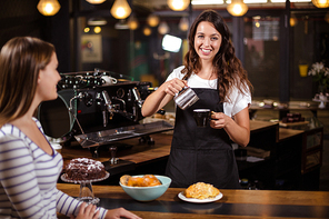 Pretty barista making cappuccino in the bar