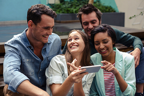 Happy friends using smartphone outside the bar