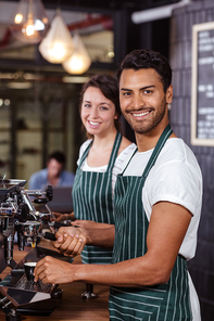 Smiling baristas using coffee machine in the bar