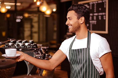 Smiling barista putting espresso on counter in the bar