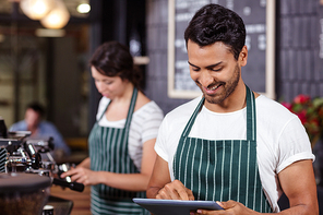 Smiling barista using tablet in the bar