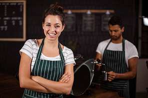 Smiling barista standing with arms crossed in the bar