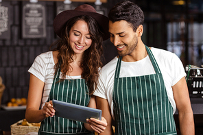 Smiling baristas using tablet in the bar