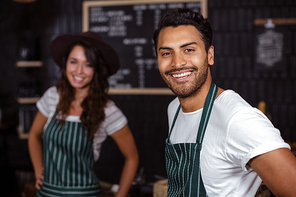 Smiling baristas looking at the camera in the bar